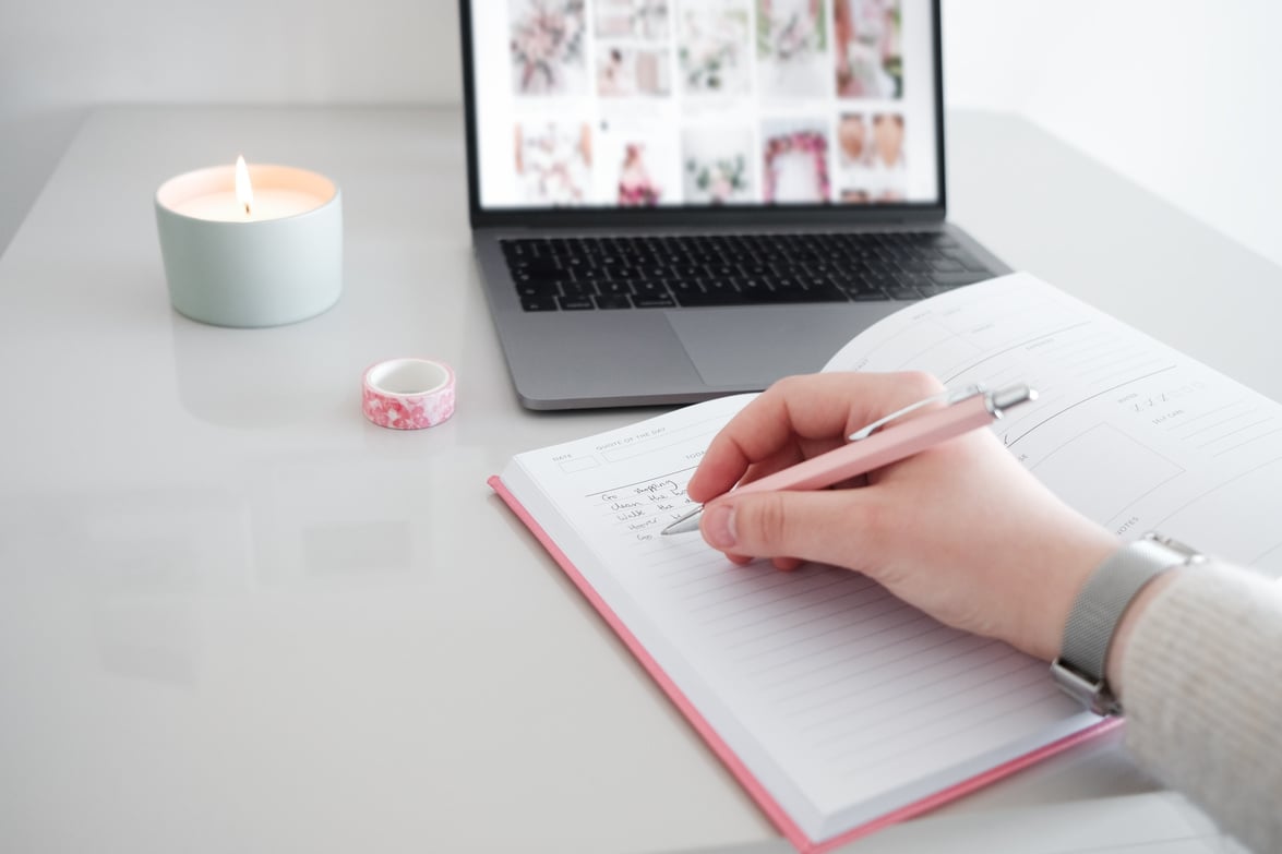 Writing notes in pink notebook.